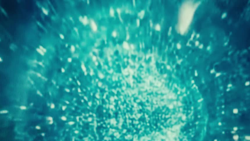 A screen shows light particles flowing on a dark background