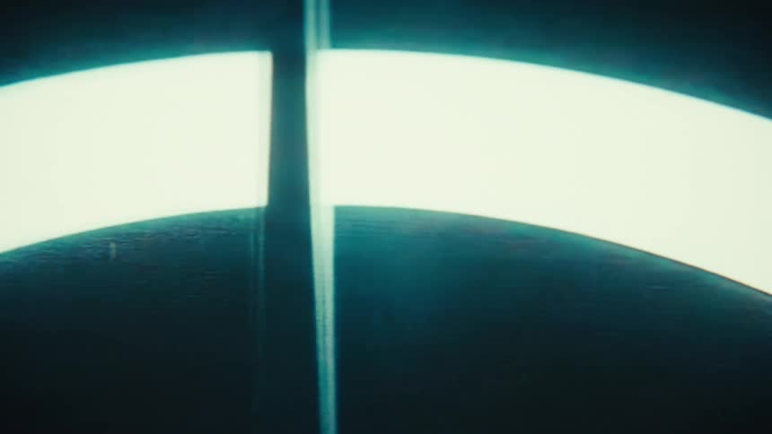 A screen shows light bands on a black background moving across the center of the frame