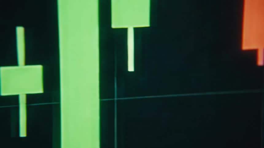 Green and orange colors of a candlestick chart contrast with the black background on a computer display