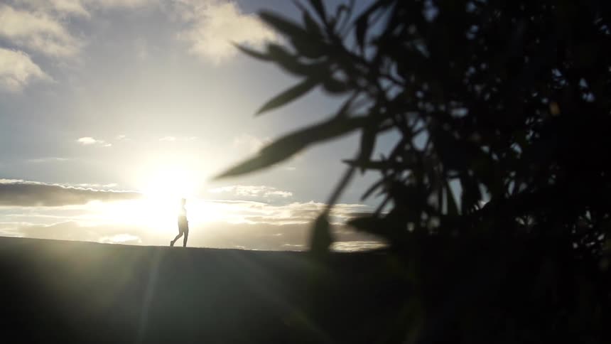 A person walking in the distance as the sun rises