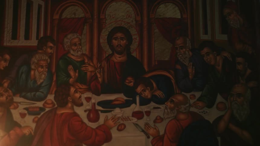 An image of the last supper is illuminated by flickering candlelight