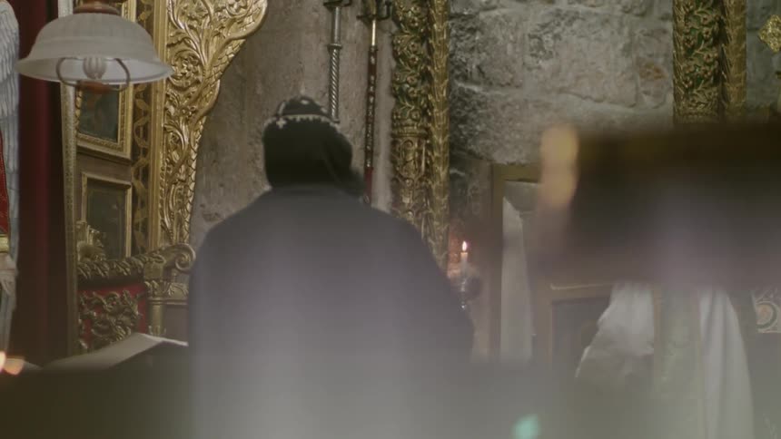 A robed clergyman stands in a church