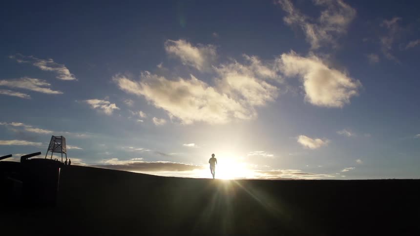 A person running as the sun rises behind