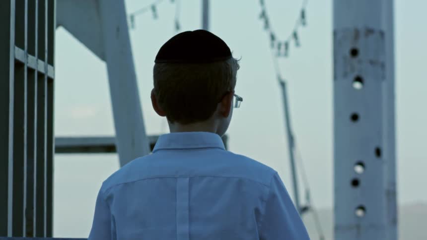 A boy standing and looking out at the water