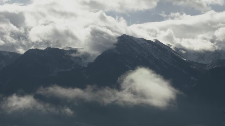 A shot shows a view of mountains with clouds moving around and through the peaks