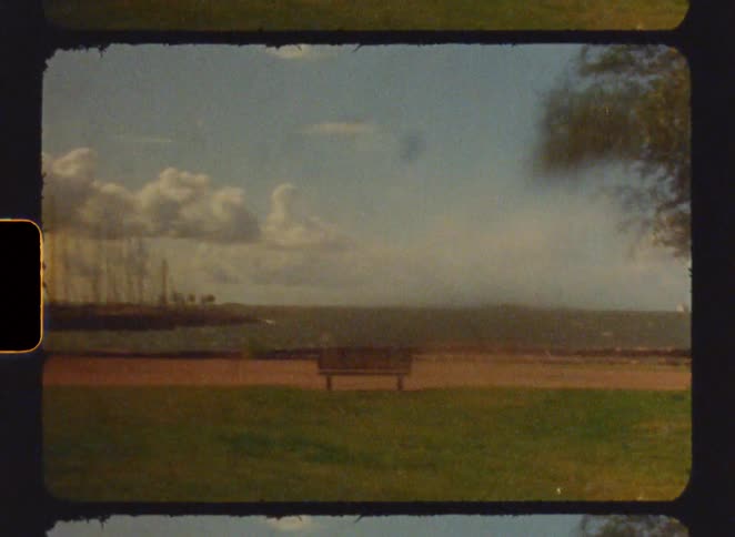 Vintage footage parkbench on the grass overlooking the coast