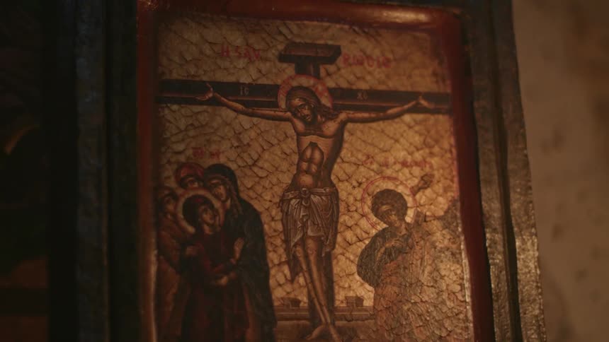 Flickering light shines on a painting of the crucifixion