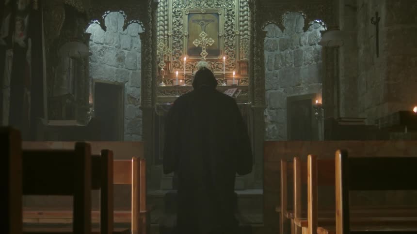 A priest blesses himself as he walks to the church altar and bows