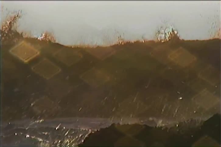 The first line shows a static wide shot of waves crashing onto a rocky coastline with diamondshaped lens flares covering the frame the second line shows a closeup of the water and rocks as the waves continue to crash and the diamondshaped flares pe