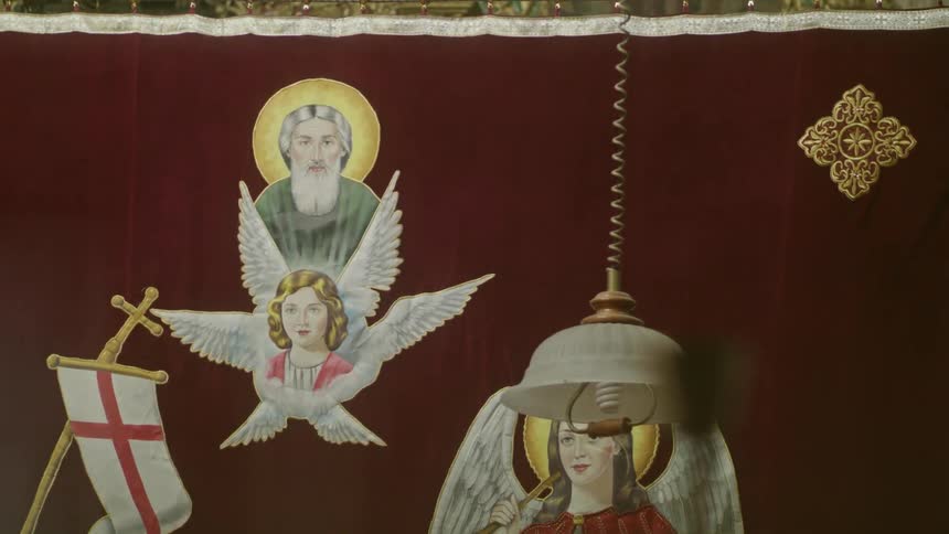 A banner with holy icons is hanging in an interior with a lamp