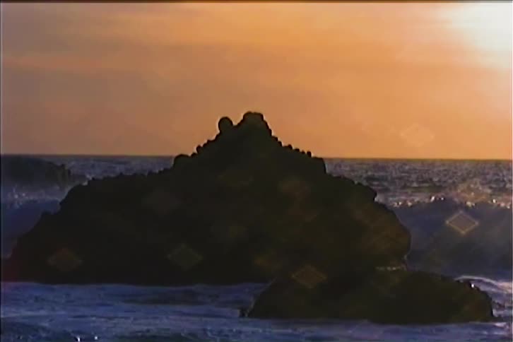 Ocean waves splashing against rocks at the coast at sunset