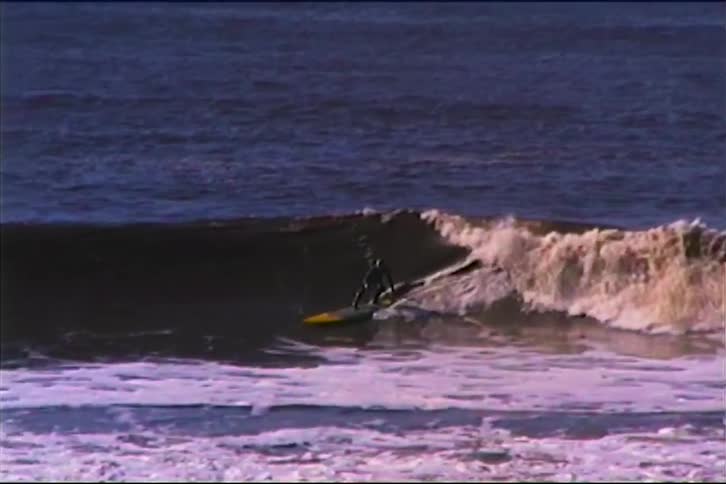 A surfer riding a curling wave almost all the way to the beach but then falls over