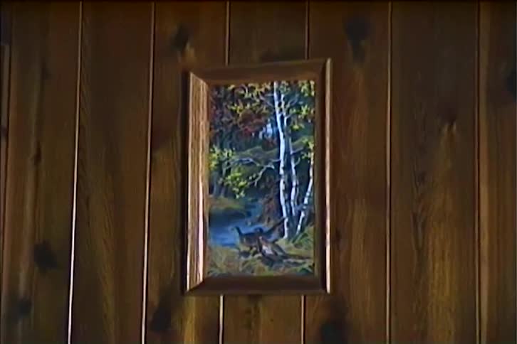 A forest painting hangs on a wall zooming in on its details