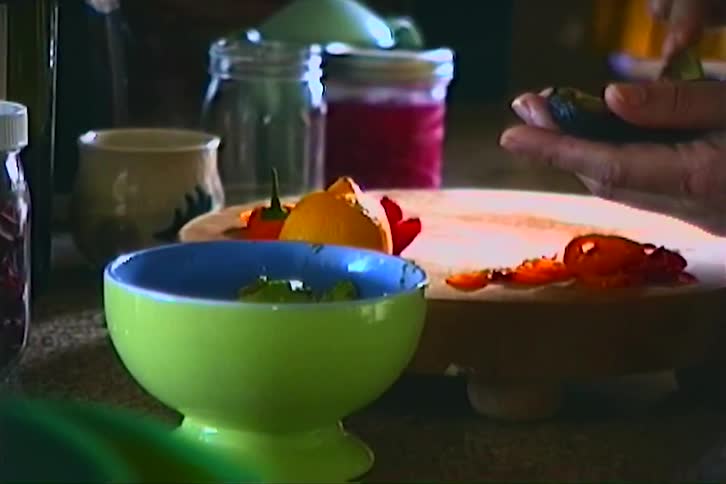A persons hands scoop the contents of an avocado with a spoon and place them into a bowl