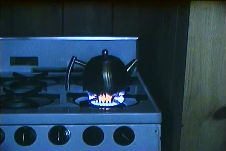 A teapot is sitting on a stove with a lit burner underneath it