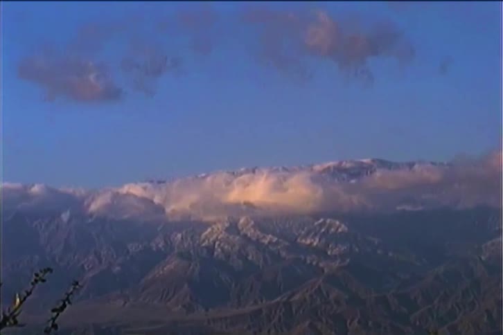 Dense smoke cloud obscures a snow dusted mountain on a winter day