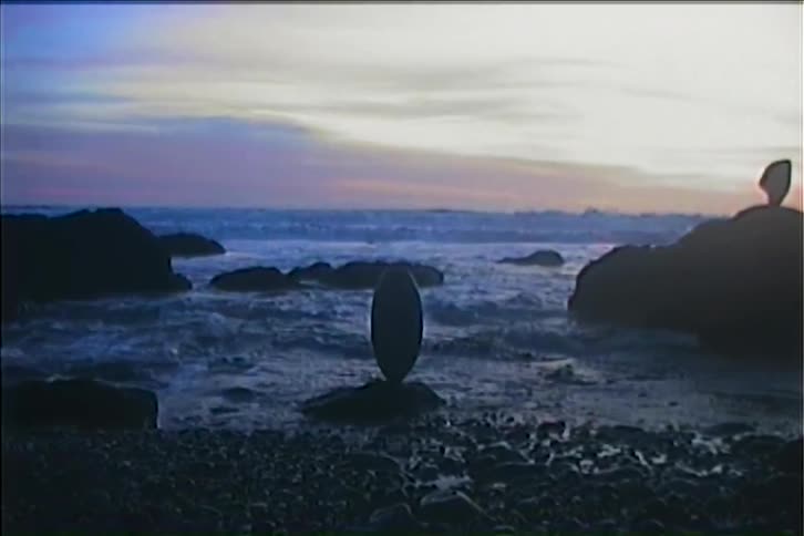 The tide hits the oval shaped rock balanced on the shore