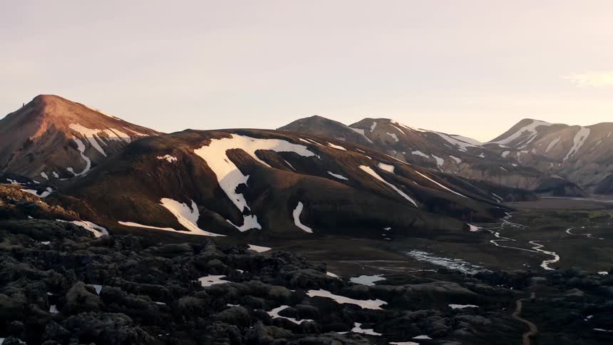 Mountains still have snow on them high above a valley