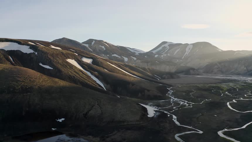 The sunlight melts the snow on the mountains