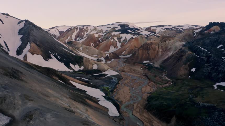 The melting snow on the mountain peak leaves a stream below