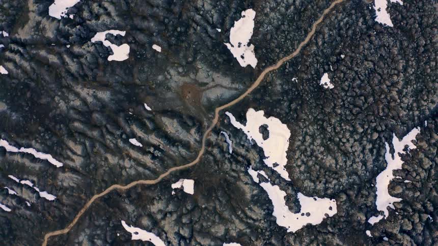 Aerial of a rocky terrain covered partly with snow during daytime in winter