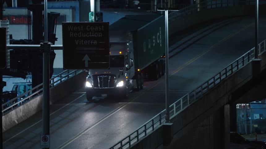 A cargo truck driven down a bridge in a metropolitan city at night