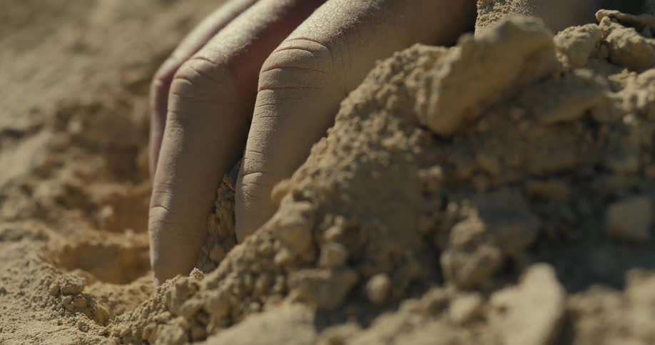 The man picks up a handful of dirt