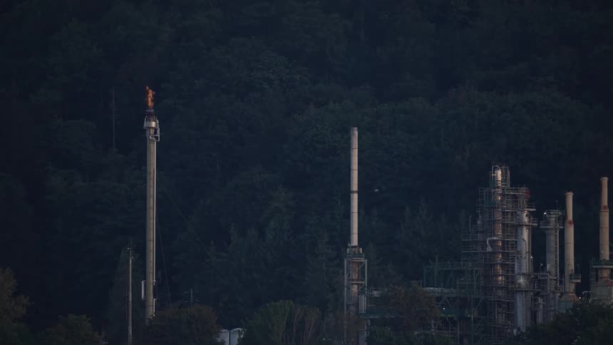 A flare stack at an industrial facility such as an oil refinery or petrochemical plant with a flame burning at the top