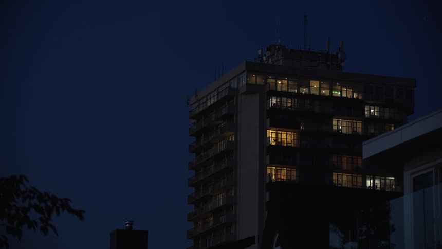 A highrise condo apartment with lights shining from different rooms at night