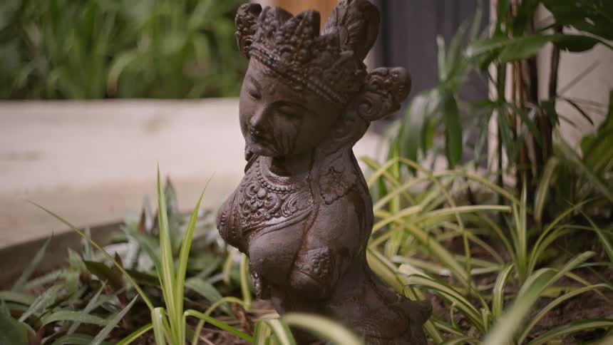 A statue of a womans torso surrounded by plants in a garden setting