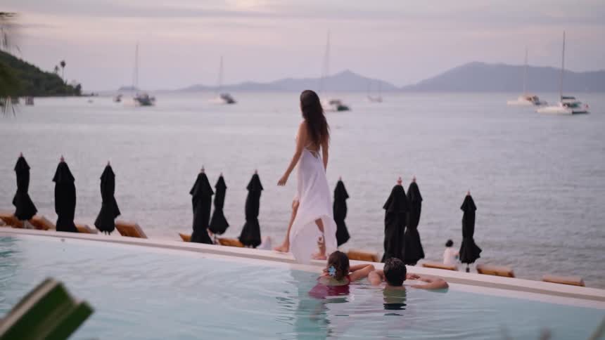 The woman walks by the pool near the shore