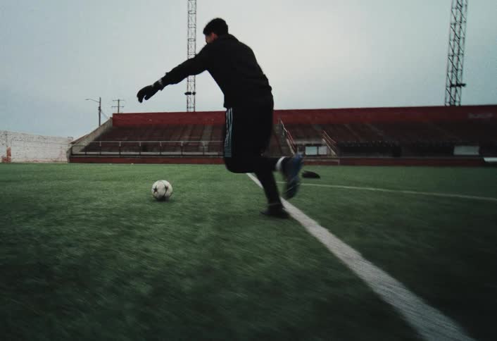 A soccer player kicks a ball on an empty field