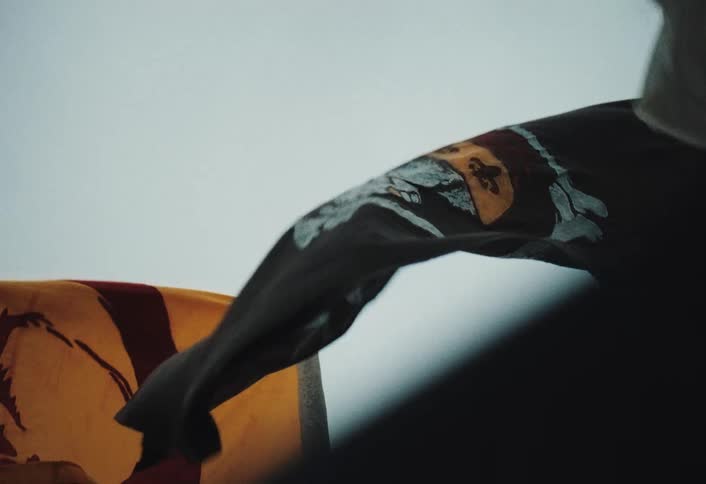 Black flag flutters in the wind with a skull and crossbones design over a yellow background with details