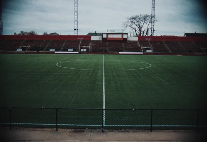 Center of a sports field showing the stands behind it and the fence in front of it