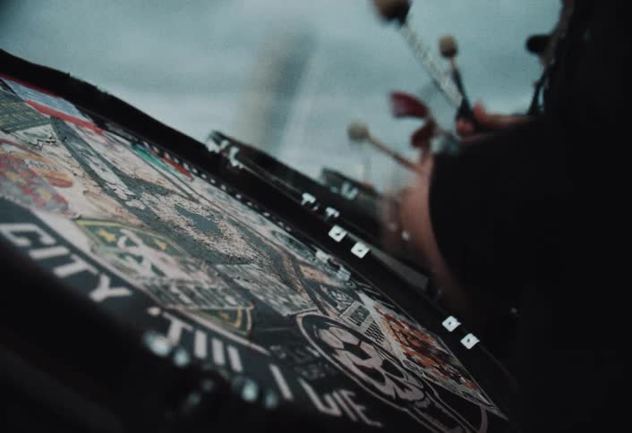 A band playing drums while people celebrate outdoors on a cloudy day