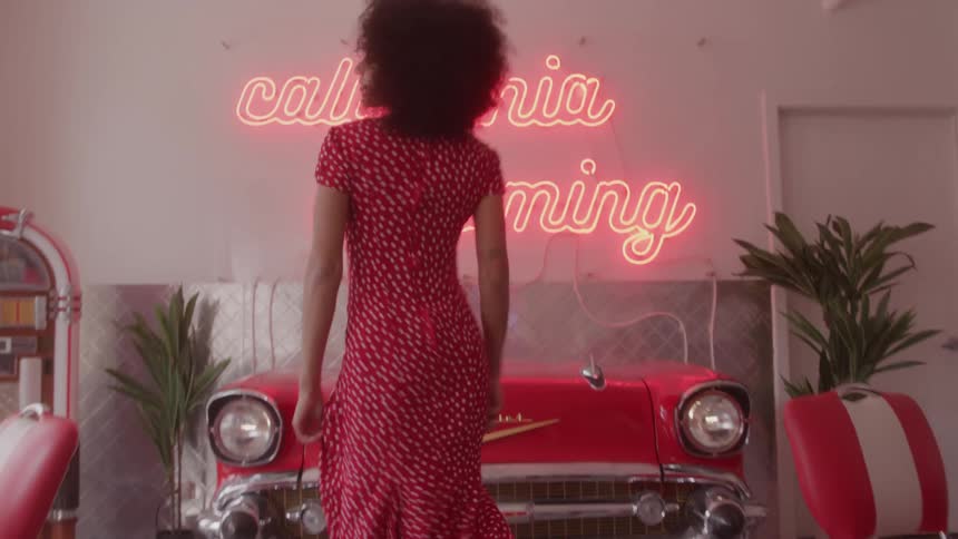 A woman dances and walks toward the camera in a cafeteria setting