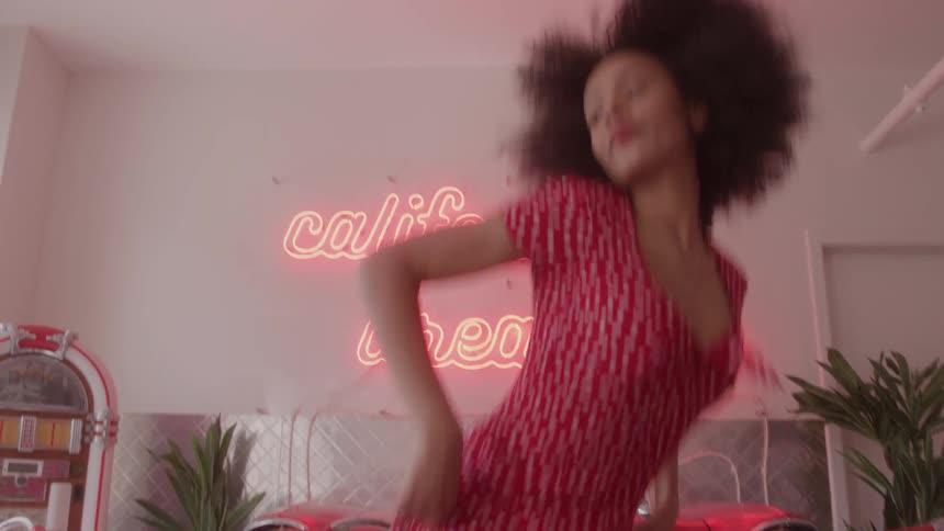 A woman wearing a red polka dot dress sits down in the restaurant