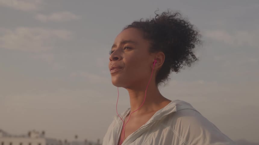 The woman is listening to earbuds outside