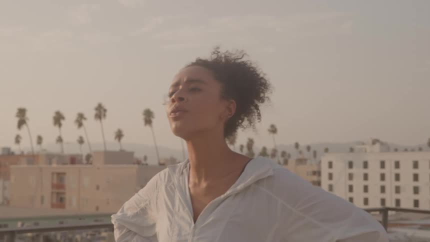 Woman stands confidently on rooftop in soft evening light