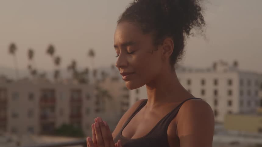 A woman practices yoga on a rooftop at sunset