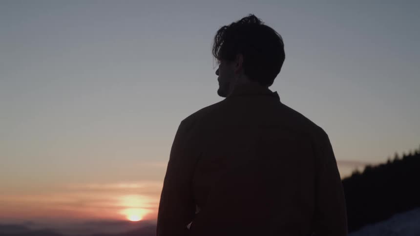 The man watches the sunrise from the mountains