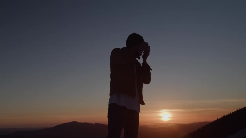 Person photographing the sunset over mountains
