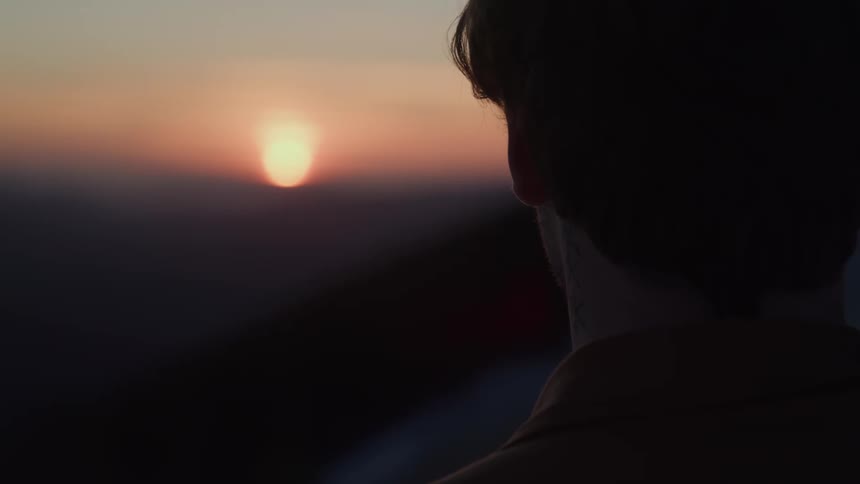 A person is looking at a sun as it sets in the sky