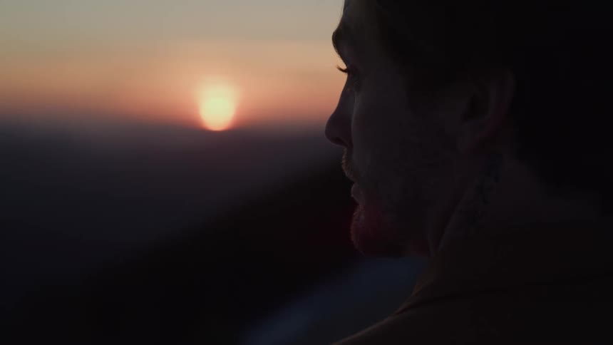 Close up portrait of a young man standing outdoors at sunset