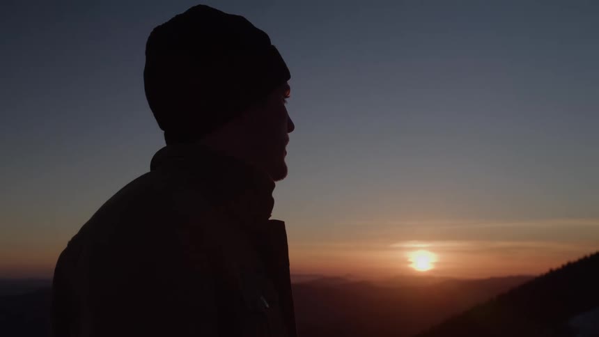 Close up portrait of a young man standing outdoors at sunset
