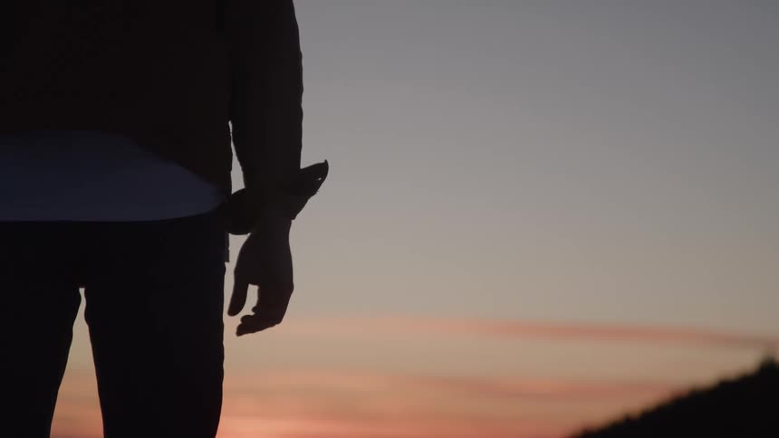 Close up of a young man standing outdoors at sunset