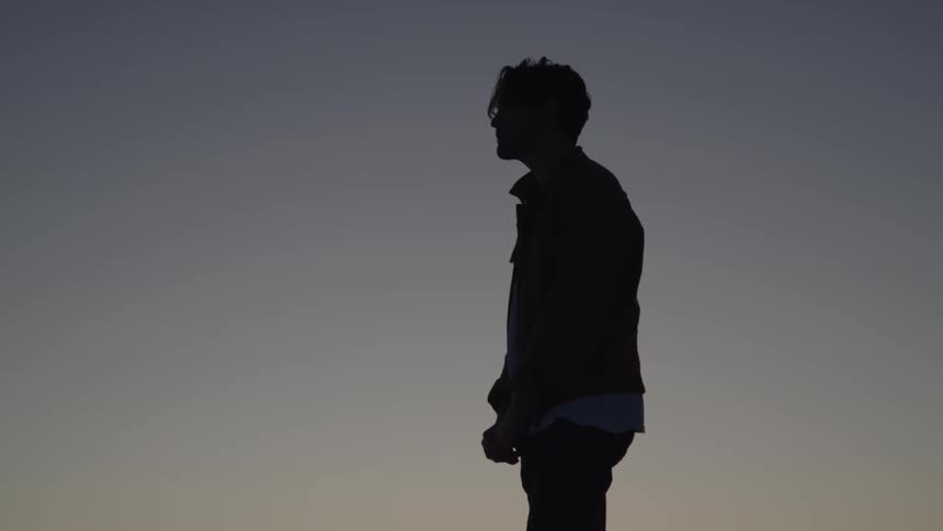 The man is standing in the shade as the sun rises
