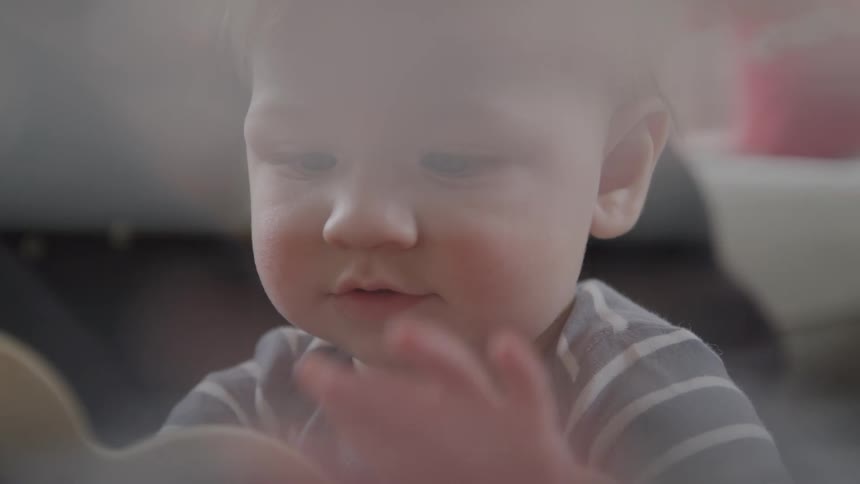 A child is sitting and moving their body and looking around while their face is in the center of the camera