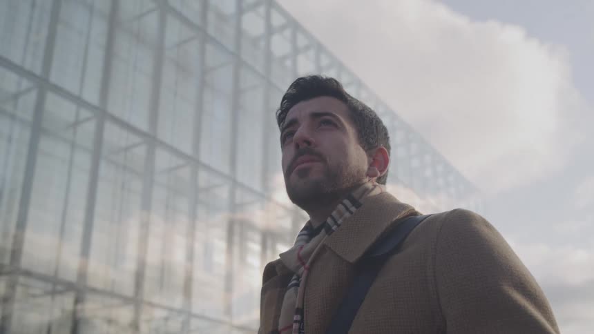 Close up portrait of a young man standing outdoors in a city during daytime