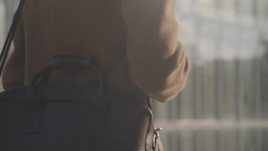 Person walking with a black leather bag